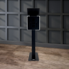 Capture Your Spin The Eclipse - DSLR Flash Photo Booth in black, with its sleek freestanding design featuring a screen and camera, is placed on a wooden floor against a dark, paneled wall.