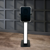Capture Your Spin A tall, rectangular The Premier - LED & DSLR Photo Booth (Black) with a digital screen stands on a wooden floor against a dark paneled wall.